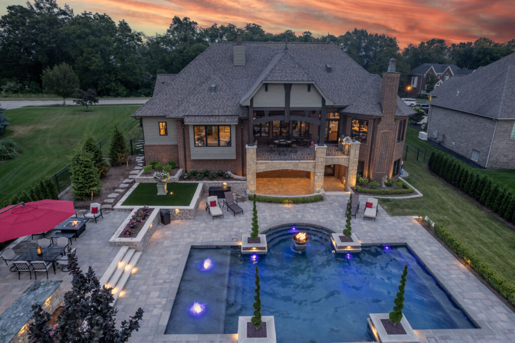Luxury backyard with a custom Gunite swimming pool, elegant landscaping, outdoor seating, and a stunning home, showcasing Tango Pools' craftsmanship.