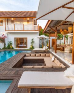 Luxury outdoor pool area featuring a modern design with a sunken seating area, surrounded by lush greenery and a stylish patio, ideal for custom pool projects by Tango Pools.