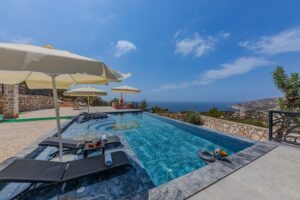 Luxury infinity pool with sun loungers and umbrellas overlooking a scenic landscape, showcasing a tranquil outdoor space ideal for relaxation and gatherings.