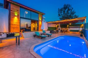 Custom Gunite pool in a beautifully lit backyard with lounge chairs, outdoor seating area, and modern architecture, showcasing outdoor living design by Tango Pools.