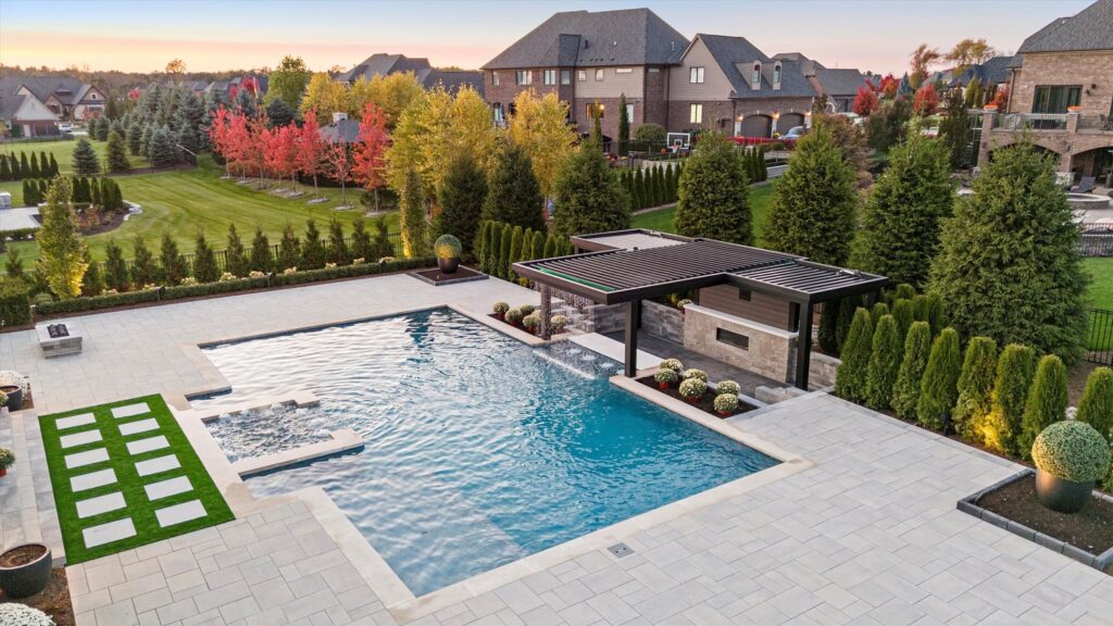 Custom Gunite pool with modern landscaping, patio area, and pergola in a residential backyard, showcasing luxury outdoor living in Northville.