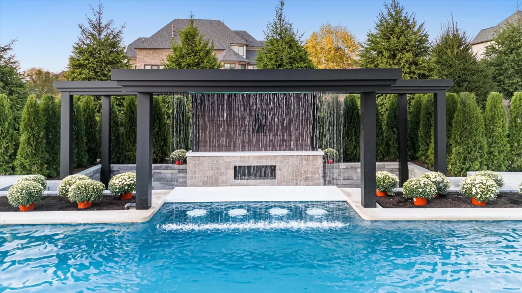 Luxury pool with modern black pergola, water feature, and landscaped planters, showcasing high-end outdoor living design by Tango Pools.